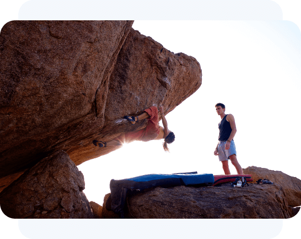 A man and a woman hiking on a steep cliff.