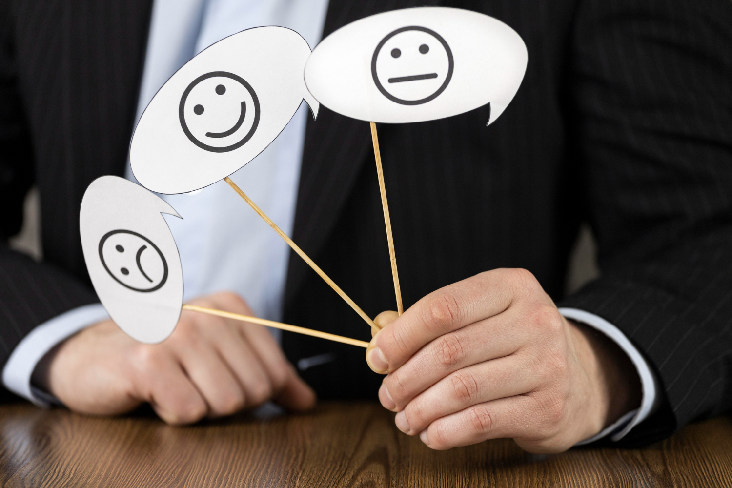 A person in a business suit holding three paper cutouts with smiley, neutral, and sad faces, representing different levels of training satisfaction rate.