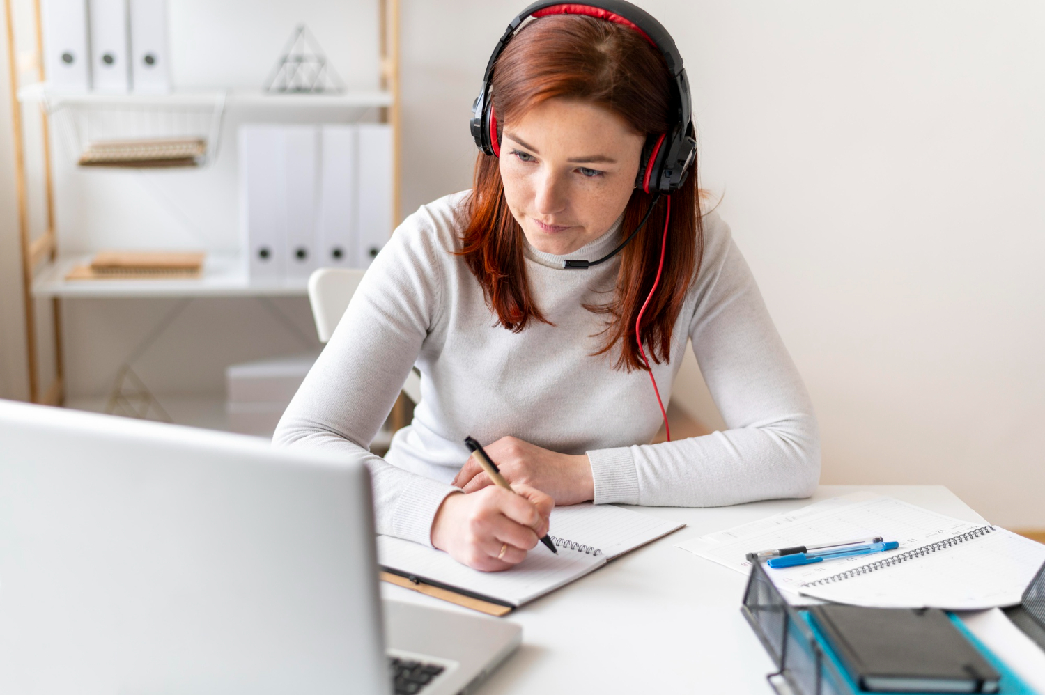 Employee participating in an online course with headset and notes, illustrating digital learning as one of the employee training methods compared in the article.