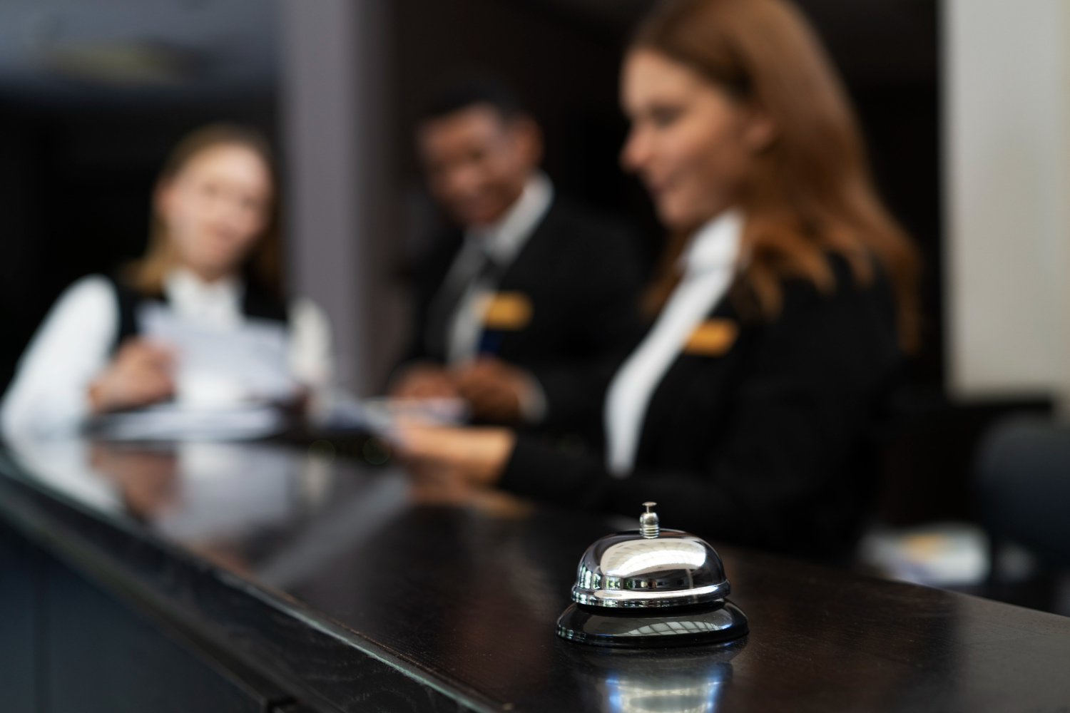 Hotel reception staff in uniform receiving instructions, representing the importance of hotel staff training to improve service quality and teamwork.